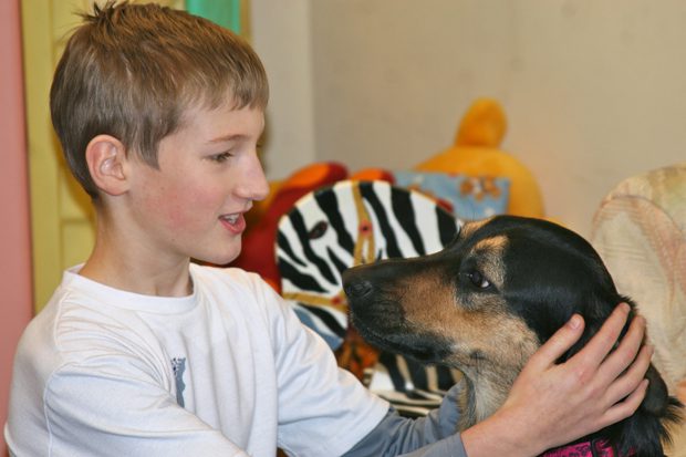 A boy holding his black and brown pet dog